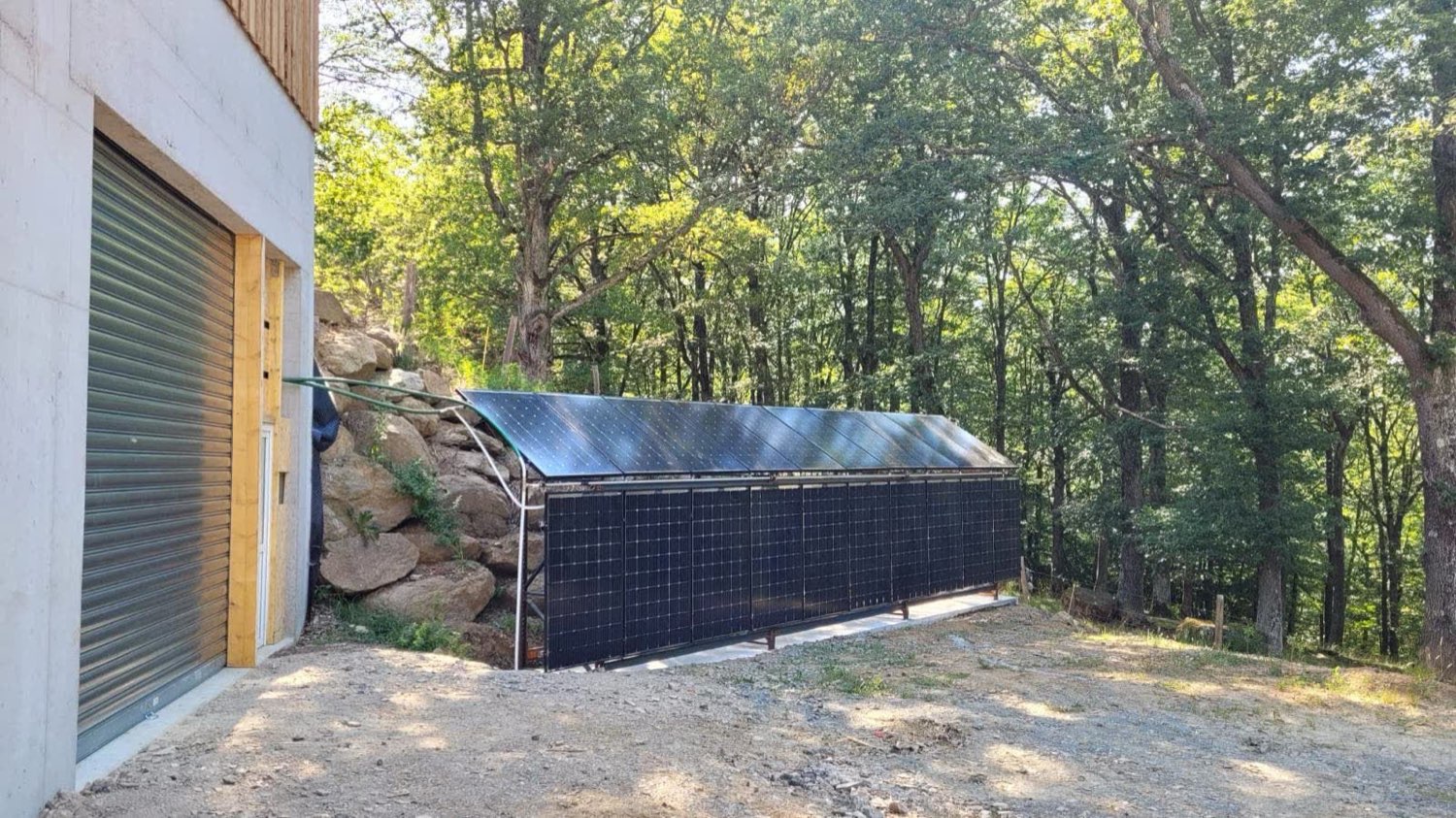 Ligne de capteurs solaires à air fixés au sol contre le bardage d'un bâtiment agricole